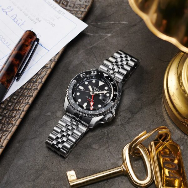 Elegant silver wristwatch with black dial on a textured surface.