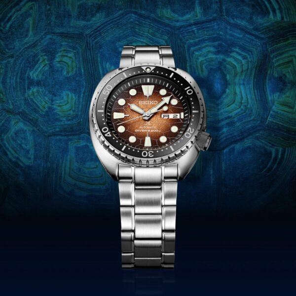 Elegant wristwatch with a metallic strap and brown dial on a blue textured background.