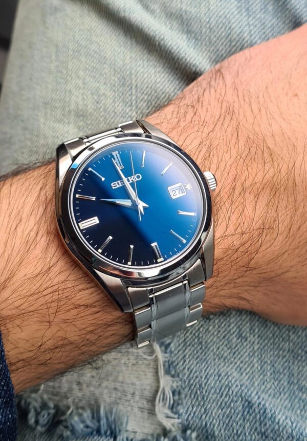 Elegant silver wristwatch with a blue dial on a person's wrist.